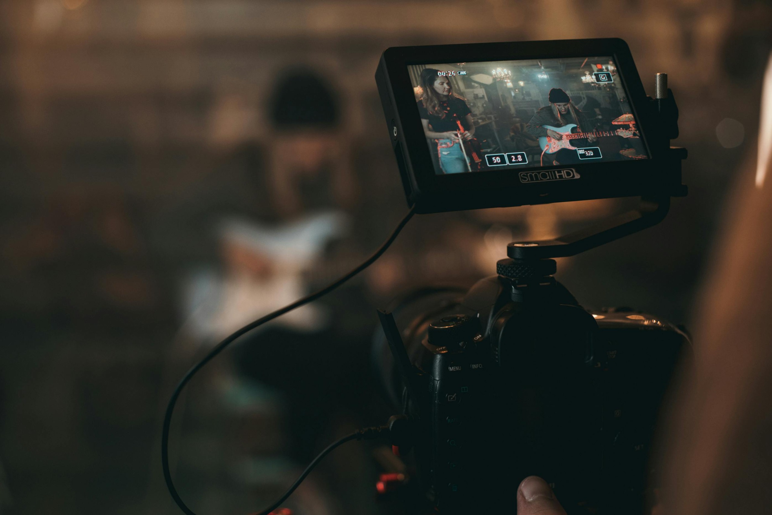 Young people recording and producing music in a studio, with a camera capturing the session