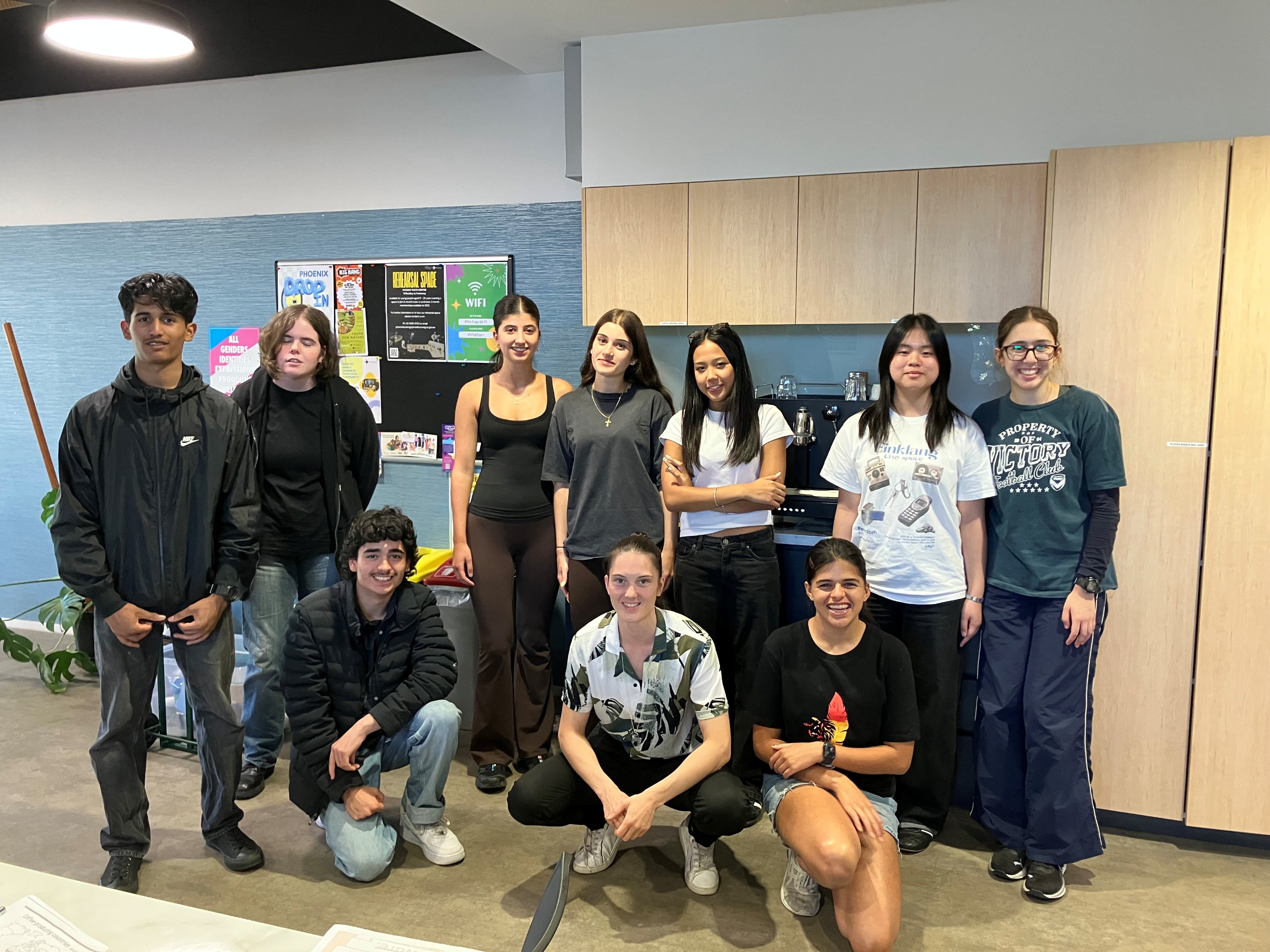 group of young people standing in front of a coffee machine smiling